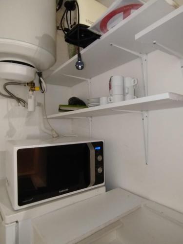 une cuisine avec un four micro-ondes et quelques étagères dans l'établissement Centre ville Bagnols sur Cèze, à Bagnols-sur-Cèze