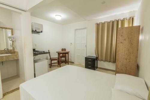 a bedroom with a white bed and a table at Pousada Ilha da Saudade in Morro de São Paulo