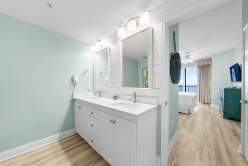 un bagno bianco con lavandino e specchio di Celadon #1408 a Panama City Beach