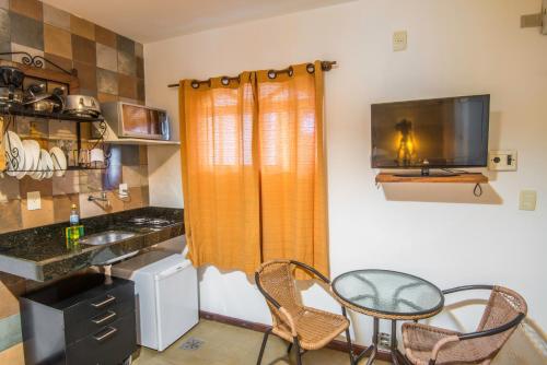 a kitchen with a table and chairs and a television at Pousada Ilha da Saudade in Morro de São Paulo