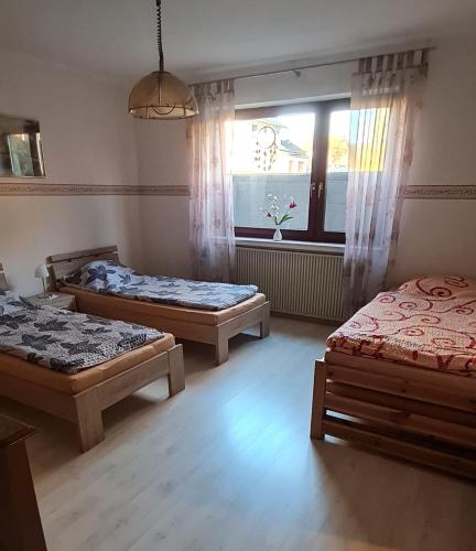 a bedroom with three beds and a window at Kleine Wohnung am Radweg in Witzenhausen