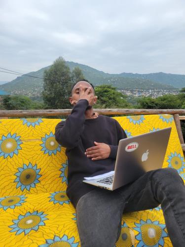 a man sitting on a couch with a laptop at EMMY'S HIDE AWAY in Iringa