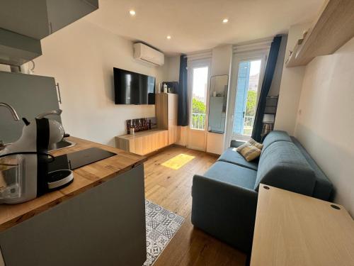un salon avec un canapé bleu et une cuisine dans l'établissement Résidence des Îles - Apt 2 Pers ultra Centre, à Antibes