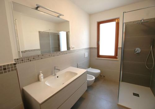 Un baño con lavabo, inodoro y espejo. en Villa Dei Golfi, en Capoliveri