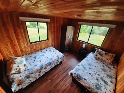 a bedroom with two beds and two windows at Cabaña Vista Hermosa 6 Personas Conaripe in Panguipulli