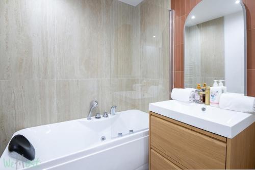 a bathroom with a white sink and a tub and a mirror at Cosy air-conditioned Studio - Place de la Bourse in Bordeaux