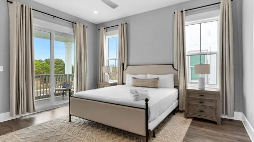 a bedroom with a bed and a balcony with windows at Queen Palm in Inlet Beach
