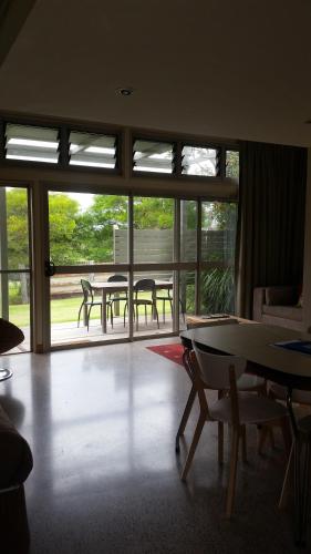 a living room with tables and chairs and windows at Elfin Hill Vineyard Accommodation in Pokolbin