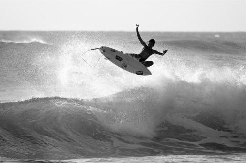 a man riding a wave on a surfboard in the ocean at Kalani Hawaii Private Lodging in Pupukea