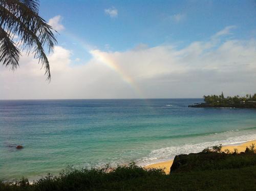 a rainbow over the ocean with a beach at Kalani Hawaii Private Lodging in Pupukea