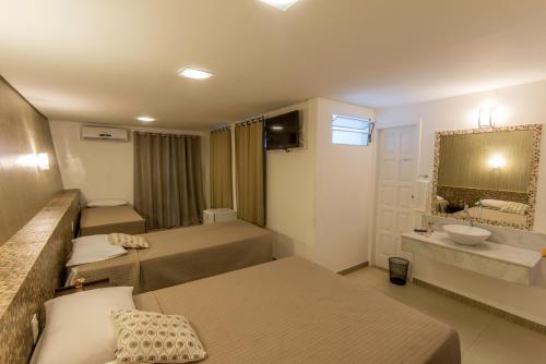 a hotel room with two beds and a sink at Pousada Ilha da Saudade in Morro de São Paulo