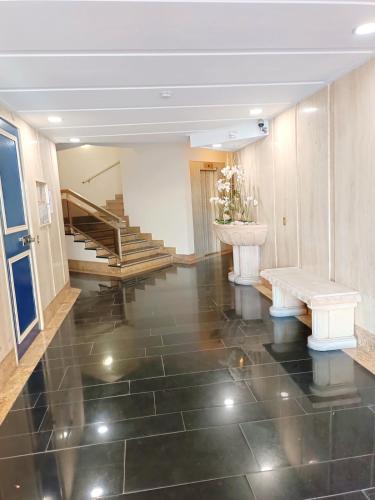 un hall avec un escalier et un sol revêtu de carrelage noir dans l'établissement Juan-Les-Pins centre, à Antibes