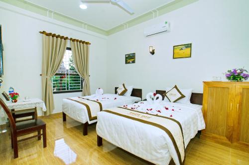 a bedroom with two beds and a table and a window at Countryside Garden Homestay in Hoi An