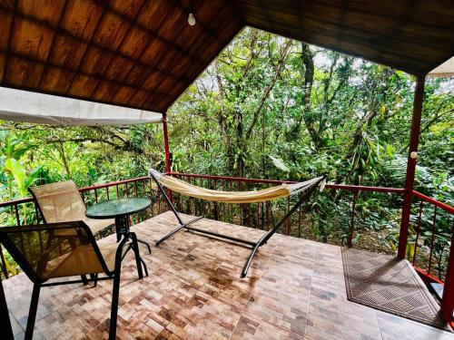 a porch with a hammock and a table and chairs at Garza del Sol Glamping Bromelia in San Rafael
