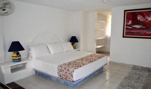 a bedroom with a white bed and two lamps at Amanwana Ecofinca in Melgar