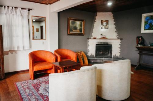 a living room with orange chairs and a fireplace at Hotel Vill' Agi in Campos do Jordão