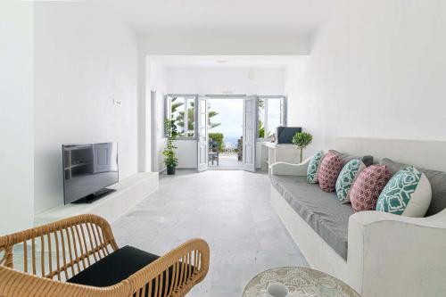 a living room with a couch and a tv at Phaos Santorini Suites in Imerovigli