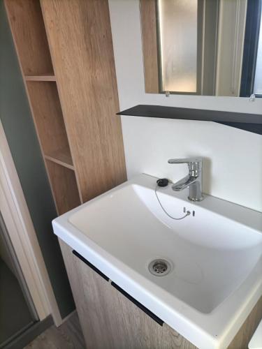 une salle de bain avec un lavabo blanc et un miroir dans l'établissement Mobilhome neuf pour 6 personnes Mer et Vacances, à Leffrinckoucke