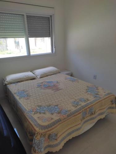 Una cama en un dormitorio con una manta. en Casa perto da Praia do Laranjal, en Pelotas