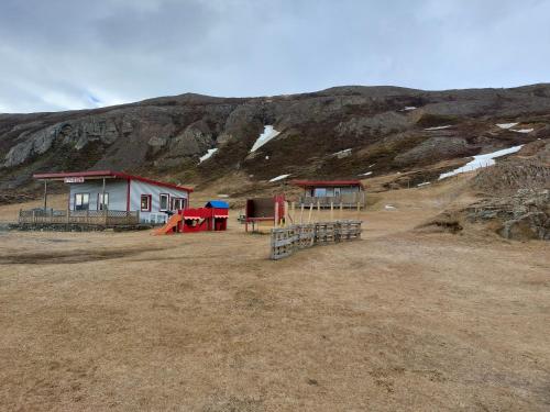 a house with a playground in front of a mountain at Ásbrandsstadir Cottages in Vopnafjörður