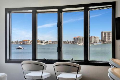 een kamer met drie stoelen en uitzicht op het water bij The Aura a Luxury Waterview Condo & heated pool in Clearwater Beach