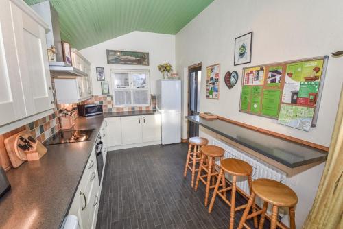 eine Küche mit einer Theke und einigen Hockern in der Unterkunft Last-Minute Escapes l Sleeps Up to 4 l A delightful thatched cottage with all the modern facilities you will require l There are 2 bedrooms, one with a double bed l the other with two singles l Carrick Thatched Cottage l WeStayBelfast in Eden