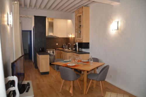 une cuisine avec une table et des chaises dans une pièce dans l'établissement Appartement atypique dans un ancien couvent, à LʼIsle-sur-la-Sorgue