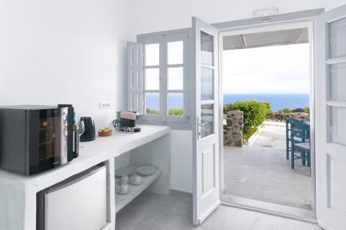 a kitchen with a microwave and a door to a patio at Phaos Santorini Suites in Imerovigli