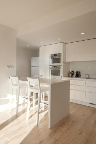 a white kitchen with a white table and chairs at Baleal Blue Sky in Ferrel