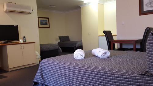 Una habitación de hotel con una cama con toallas. en Gateway Motor Inn, en Broken Hill