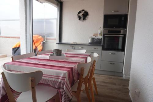 une salle à manger avec une table et des chaises et une cuisine dans l'établissement L'Oasis 4 personnes 6 Piscines Terrasse Vue petit Port, au Barcarès