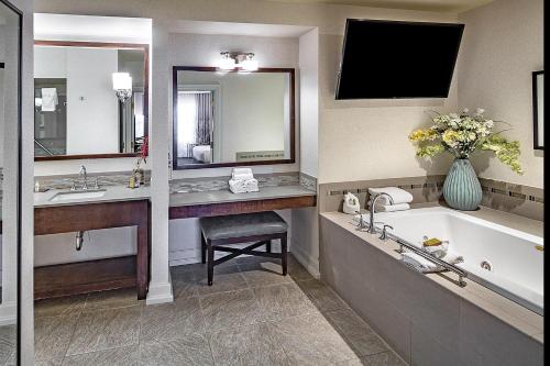 a bathroom with a tub and a sink and a mirror at DoubleTree by Hilton Modesto in Modesto