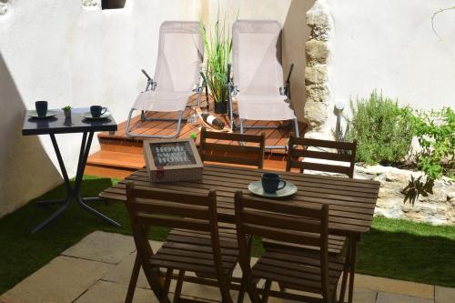 - une table en bois avec des chaises et un ordinateur portable sur la terrasse dans l'établissement Maison en coeur de ville, à LʼIsle-sur-la-Sorgue
