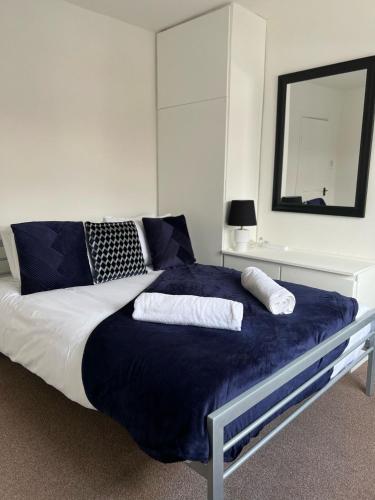 a bedroom with a large bed with blue sheets and a mirror at Olive Lodge in Southampton