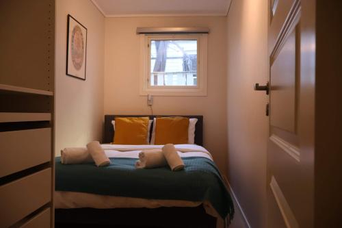 a bedroom with a bed with pillows and a window at Dinbnb Apartments I Charming 3-Bedroom in the Heart of the City in Bergen