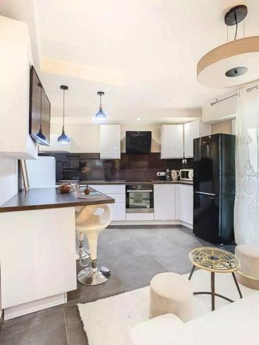 une cuisine avec des armoires blanches et un réfrigérateur noir dans l'établissement F3 4 pers 15 min Palace Cannes, à Cannes