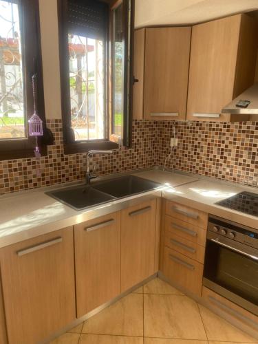a kitchen with wooden cabinets and a sink at Elani Apartments Lofos Elanis 2 in Kassandria