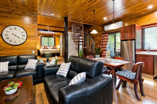 a living room with leather furniture and a clock on the wall at The Mouses House Rainforest Retreat in Springbrook