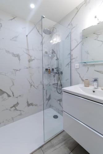 une salle de bain blanche avec une douche et un lavabo dans l'établissement Apparemment charmant au cœur du Suquet, à Cannes