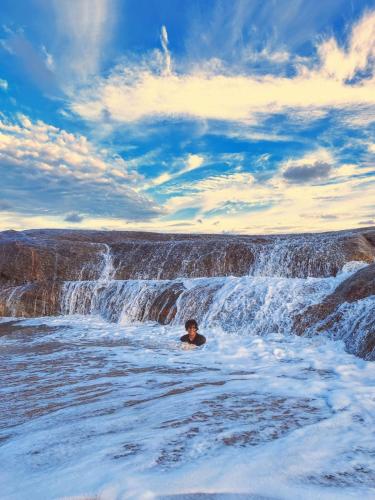 a man in the water in front of a waterfall at Garnet Yala Beach in Kirinda