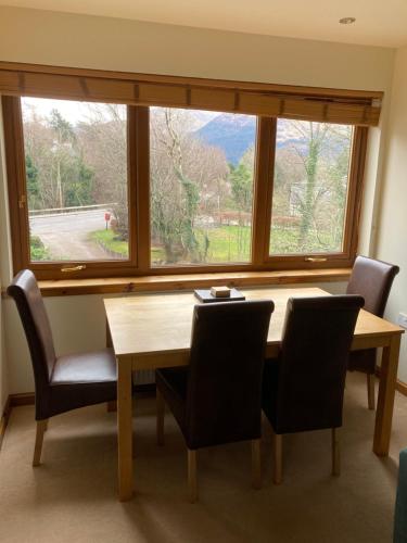 a dining room table with chairs and a large window at Springbank Apartment - Sleeps 4 - Pet Friendly in Fort William