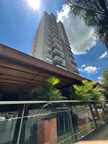 a tall building with palm trees in front of it at Hotel Santa Ana Medellin in Medellín