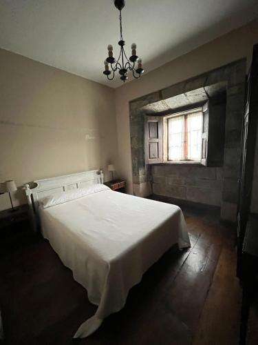 a bedroom with a white bed and a window at Palacio Conde Toreno in Malleza