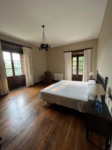 a bedroom with a large bed and wooden floors at Palacio Conde Toreno in Malleza