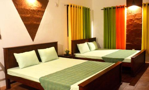 a hotel room with two beds with colorful curtains at Pelican View Cottages in Kataragama