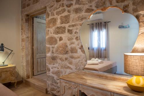 a mirror in a room with a stone wall at Gravel Aegina House in Aegina