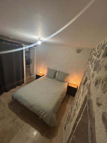 a bedroom with a bed with two lamps on it at Petite maison en pierre au calme in Lavardac