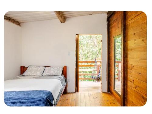 a bedroom with a bed and a sliding glass door at Chalé Foroni in Cunha
