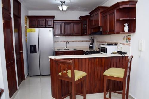 a kitchen with wooden cabinets and a white refrigerator at Relax in this apartment in Santiago de los Caballeros