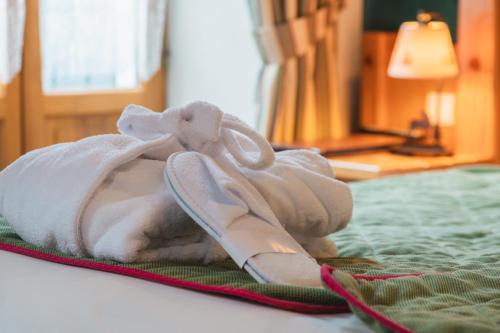 a pile of towels and shoes on a bed at Hôtel Le Bois Joli in Cauterets